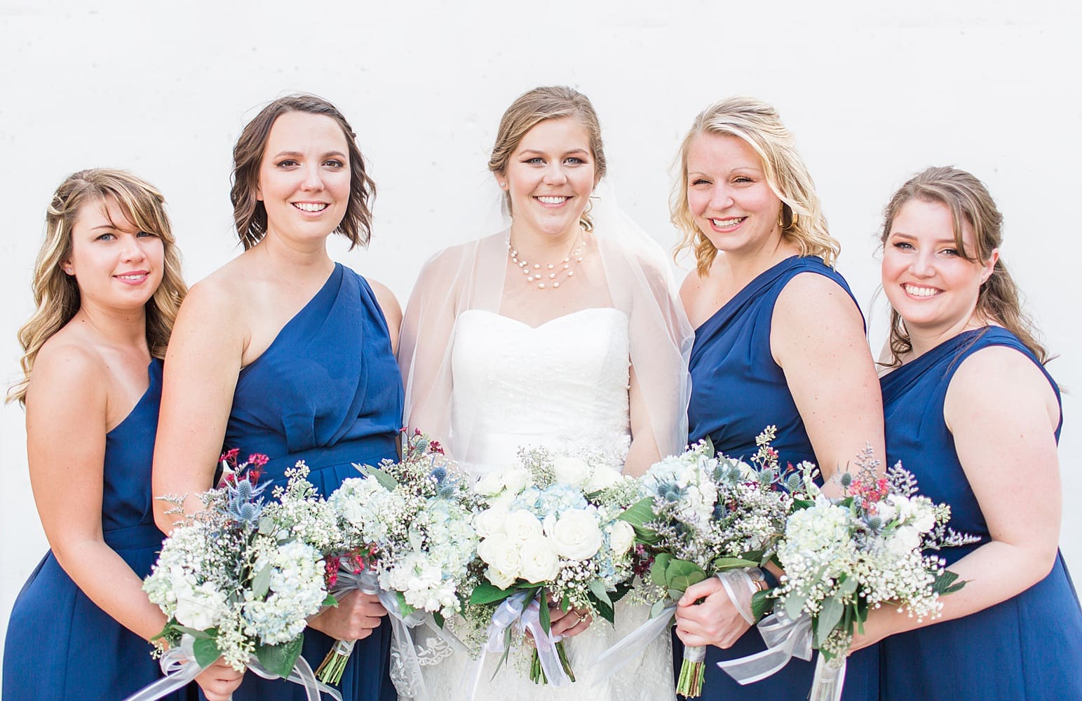 Arielle Peters Photography | Bride and bridesmaids holding bouquets outside on wedding day in Syracuse, Indiana.