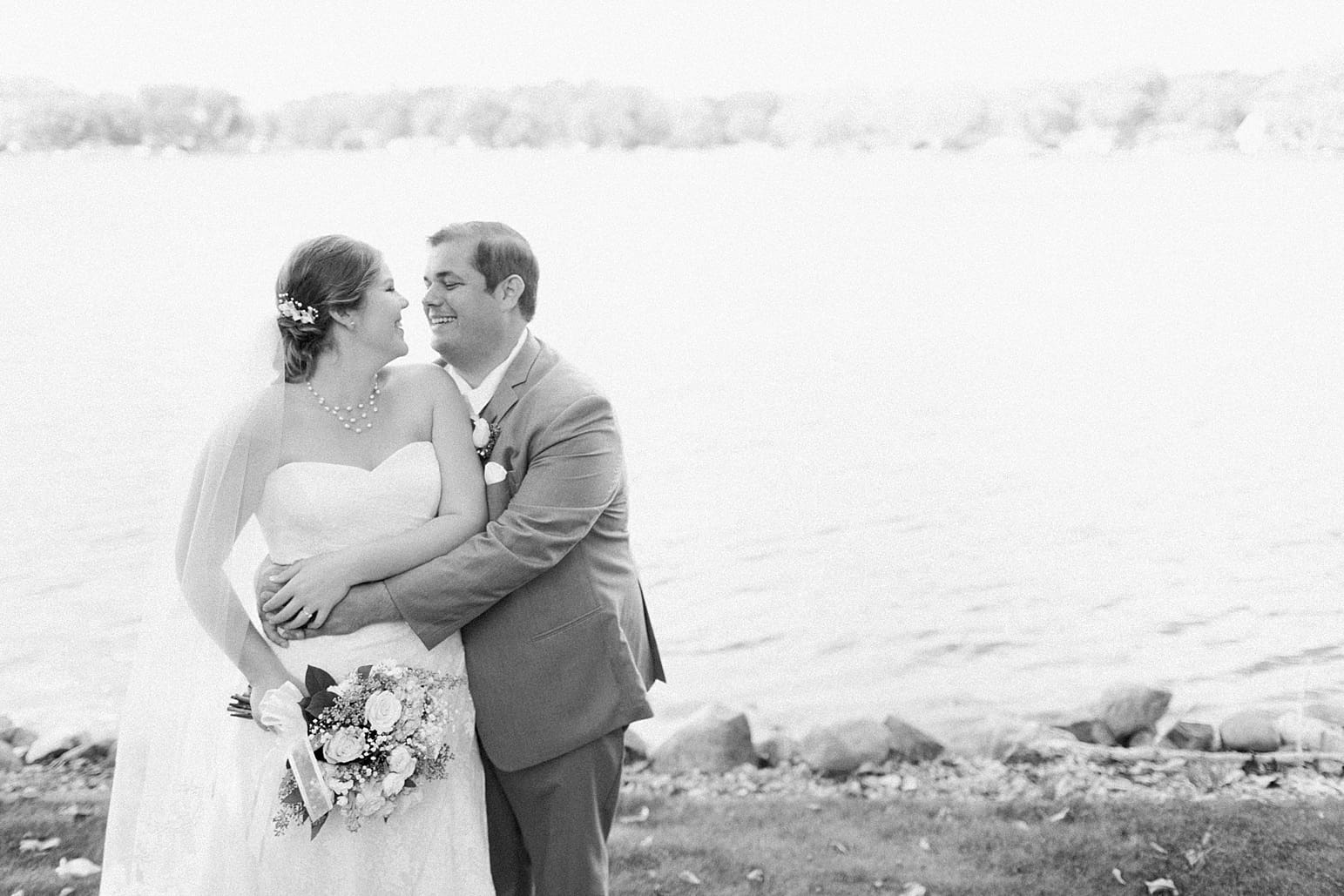 Arielle Peters Photography | Bride and groom laughing next to lake on wedding day in Syracuse, Indiana.