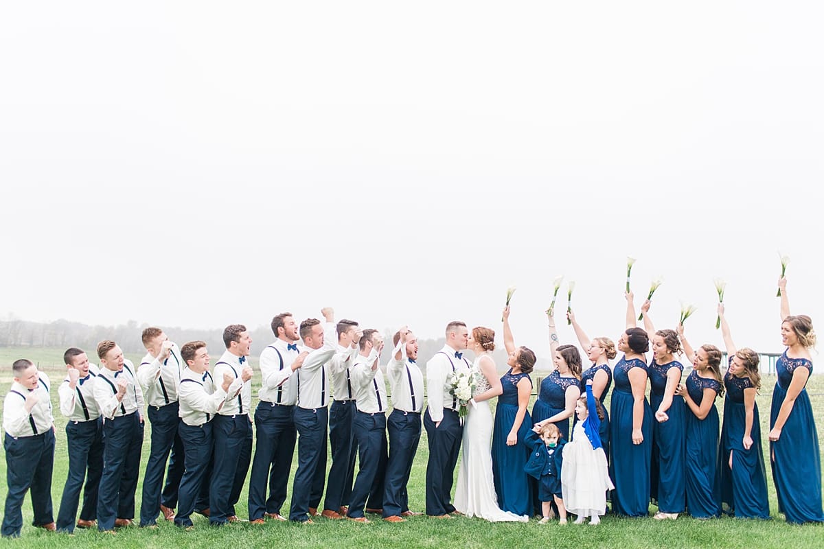 Arielle Peters Photography | Wedding party cheering in open green field on gloomy wedding day in Huntington, Indiana.
