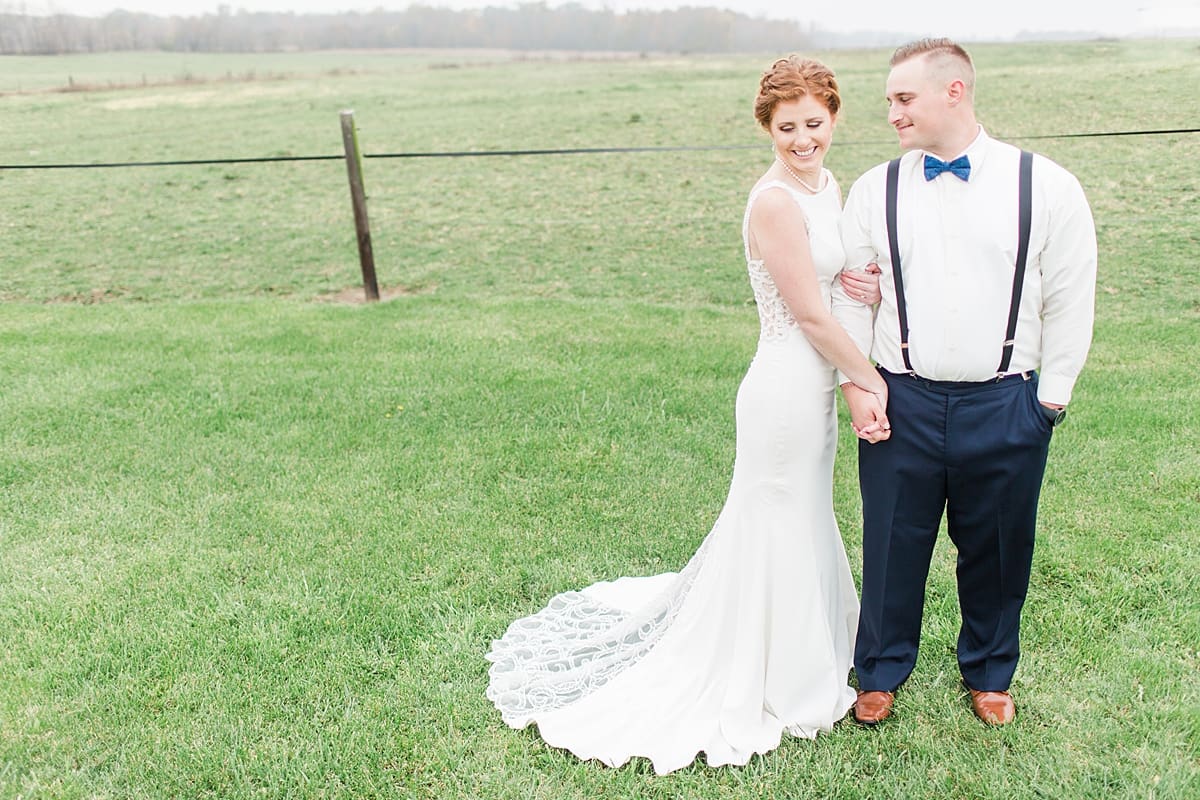 Arielle Peters Photography | Bride and groom holding hands in open green field on gloomy wedding day in Huntington, Indiana.