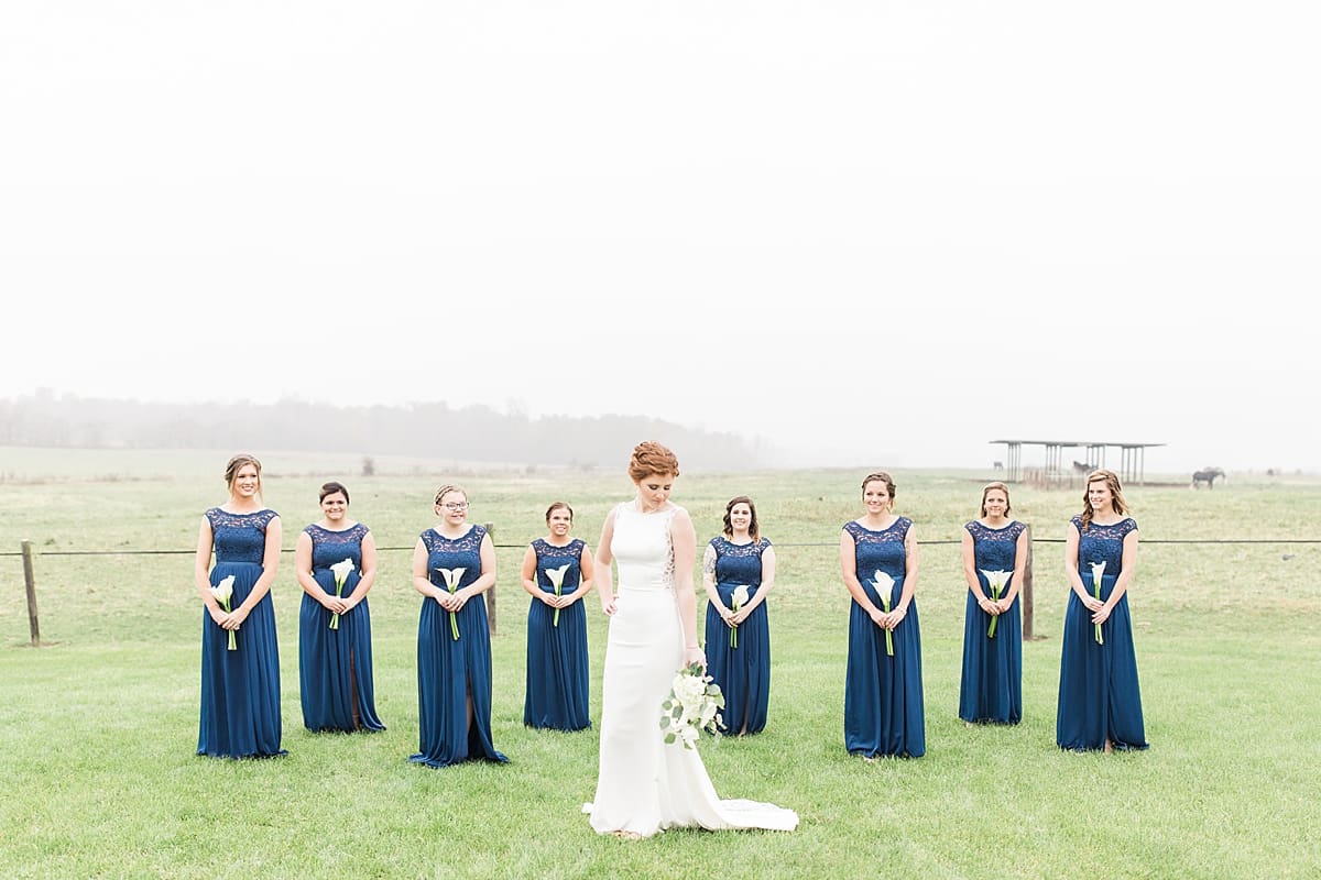 Arielle Peters Photography | Bride and bridesmaids staggered in open green field on gloomy wedding day in Huntington, Indiana.