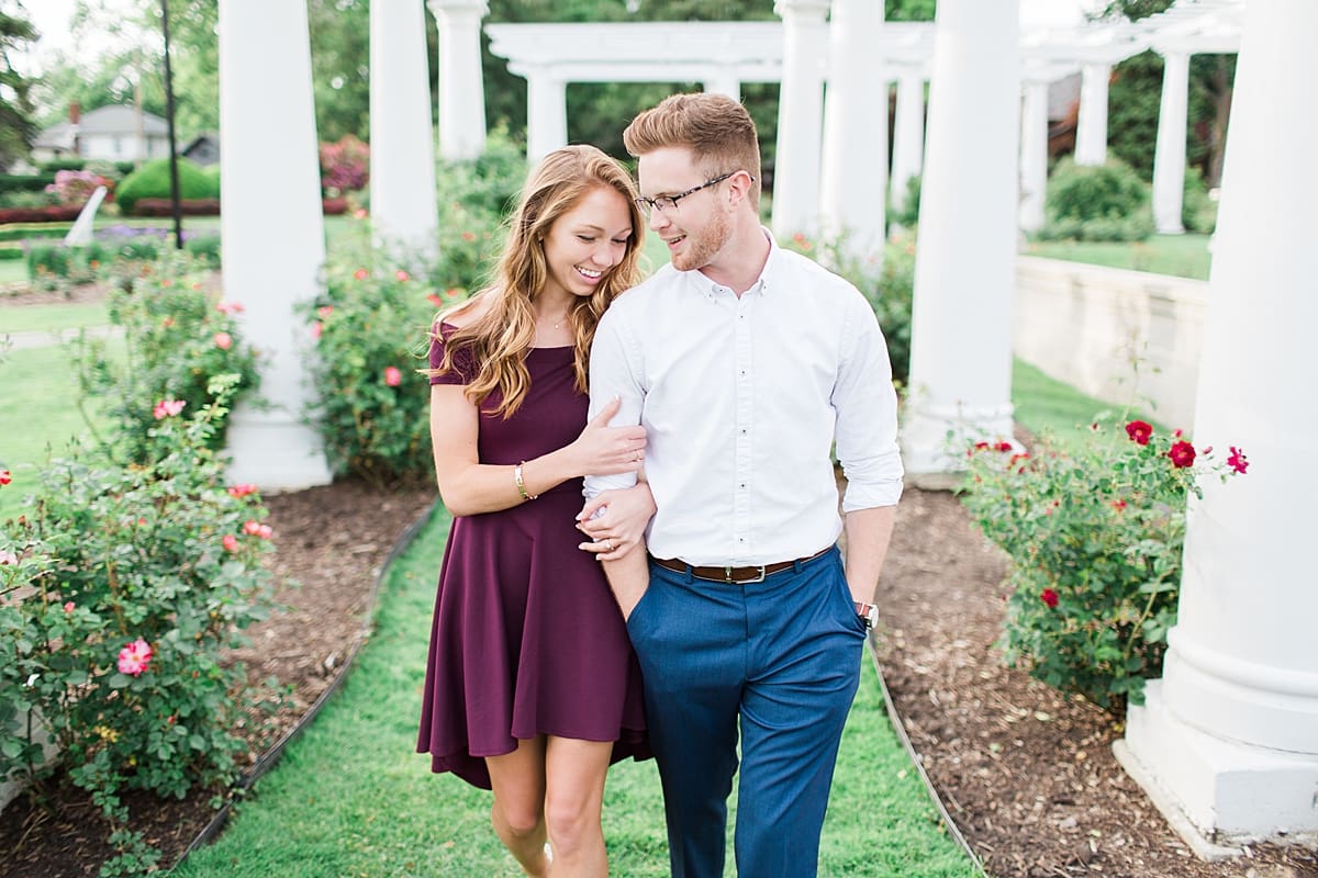 Arielle Peters Photography | Couple walking arm in arm in rose garden for summer engagement photos.