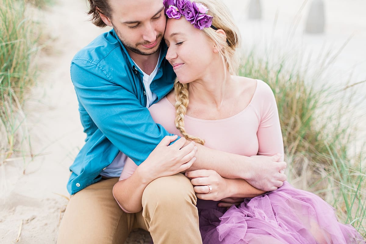 Arielle Peters Photography | Couple taking engagement photos sitting on the beach.