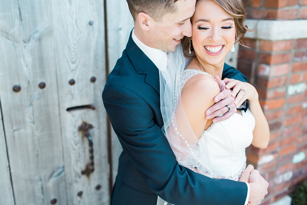 Arielle Peters Photography | Groom holding bride next to old wooden doors on wedding day.