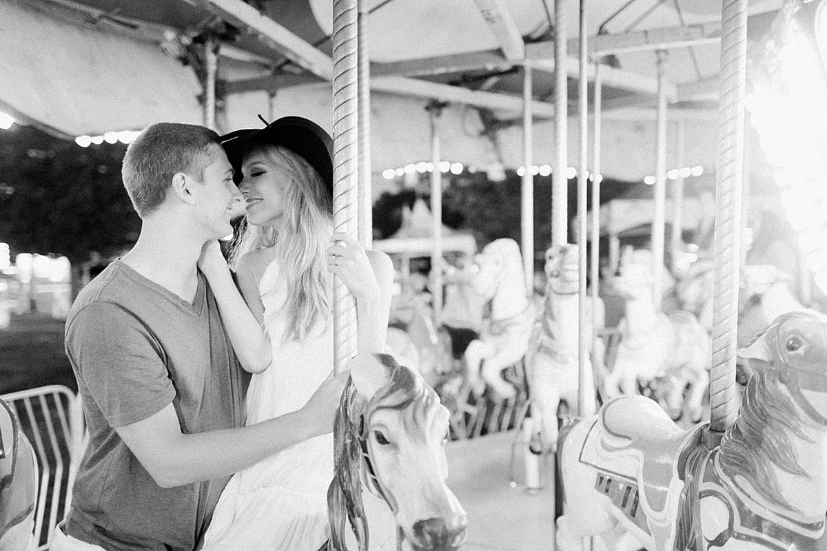 Arielle Peters Photography | Young couple almost kissing on carousel while taking summer engagement photos.