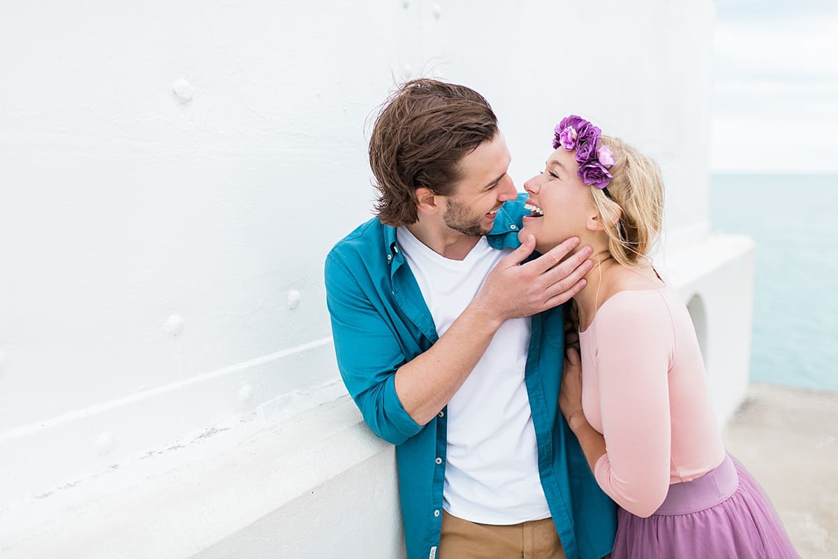 Arielle Peters Photography | Young couple laughing on dock next to water taking summer engagement photos.