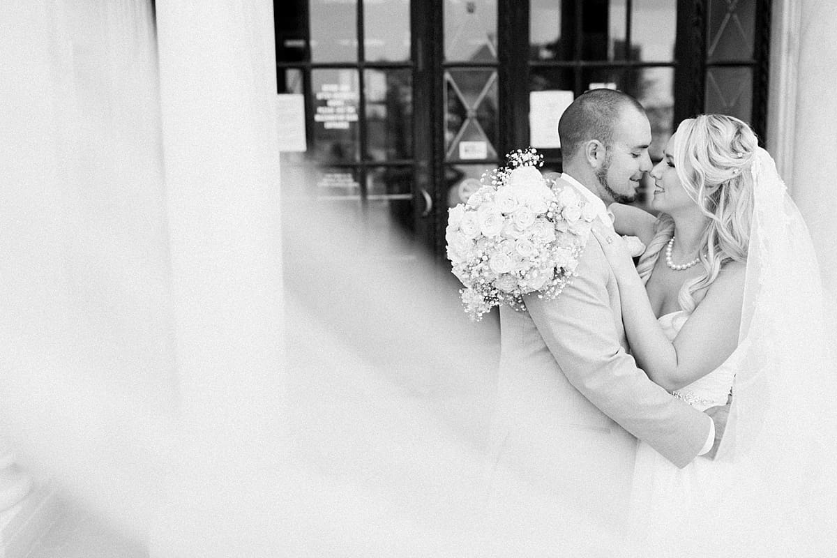 Arielle Peters Photography | Bride and groom almost kissing next to large glass doors on wedding day.