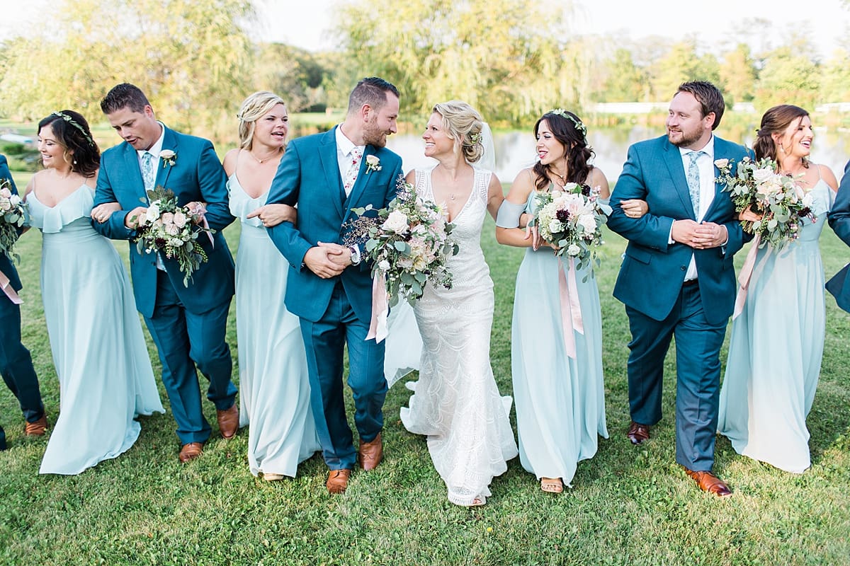 Arielle Peters Photography | Wedding party walking through open field next to pond on summer wedding day.