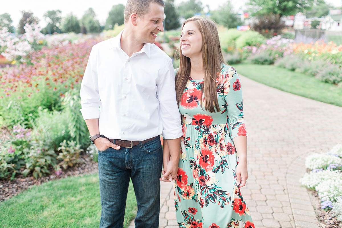 Arielle Peters Photography | Young couple holding hands on garden path taking summer engagement photos.