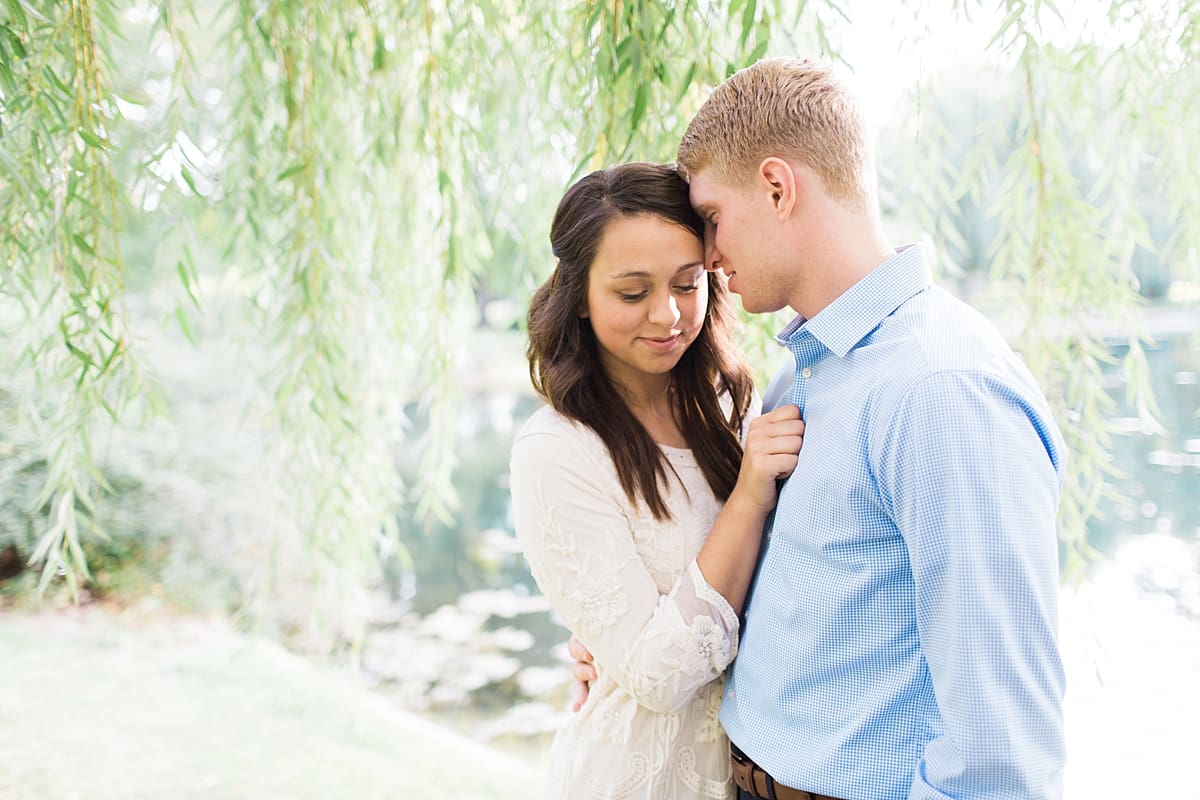 Arielle Peters Photography | Young couple underneath willow tree next to pond taking summer engagement photos.