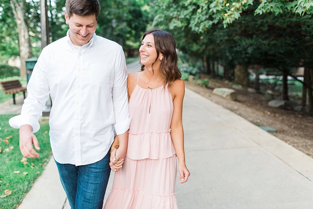 Arielle Peters Photography | Young couple holding hands walking through the park taking summer engagement photos.