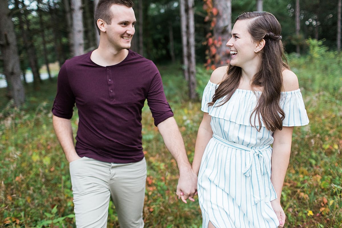 Arielle Peters Photography | Young couple holding hands in forest taking engagement photos.