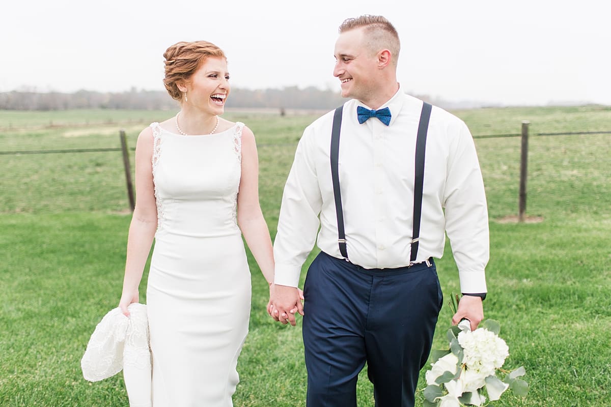 Arielle Peters Photography | Bride and groom holding hands walking in open field on cloudy wedding day.