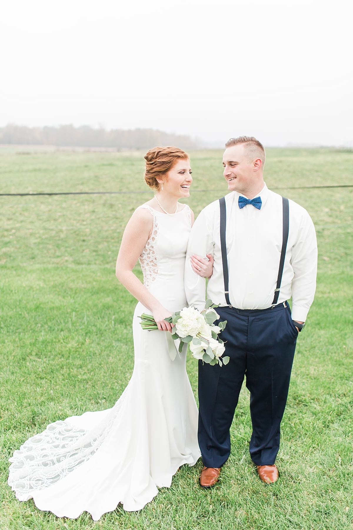 Arielle Peters Photography | Bride and holding groom's arm in open green field on gloomy wedding day.