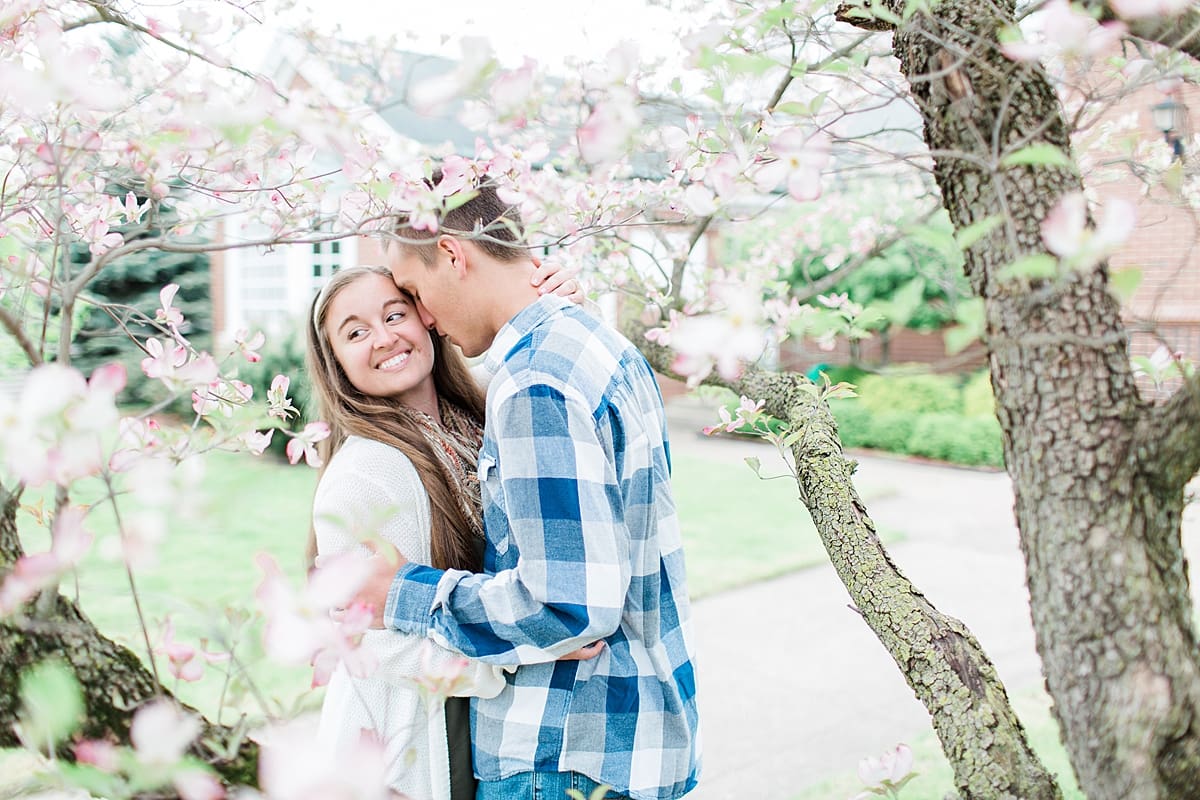 Arielle Peters Photography | Young couple kissing under blossom tree taking spring engagement photos.