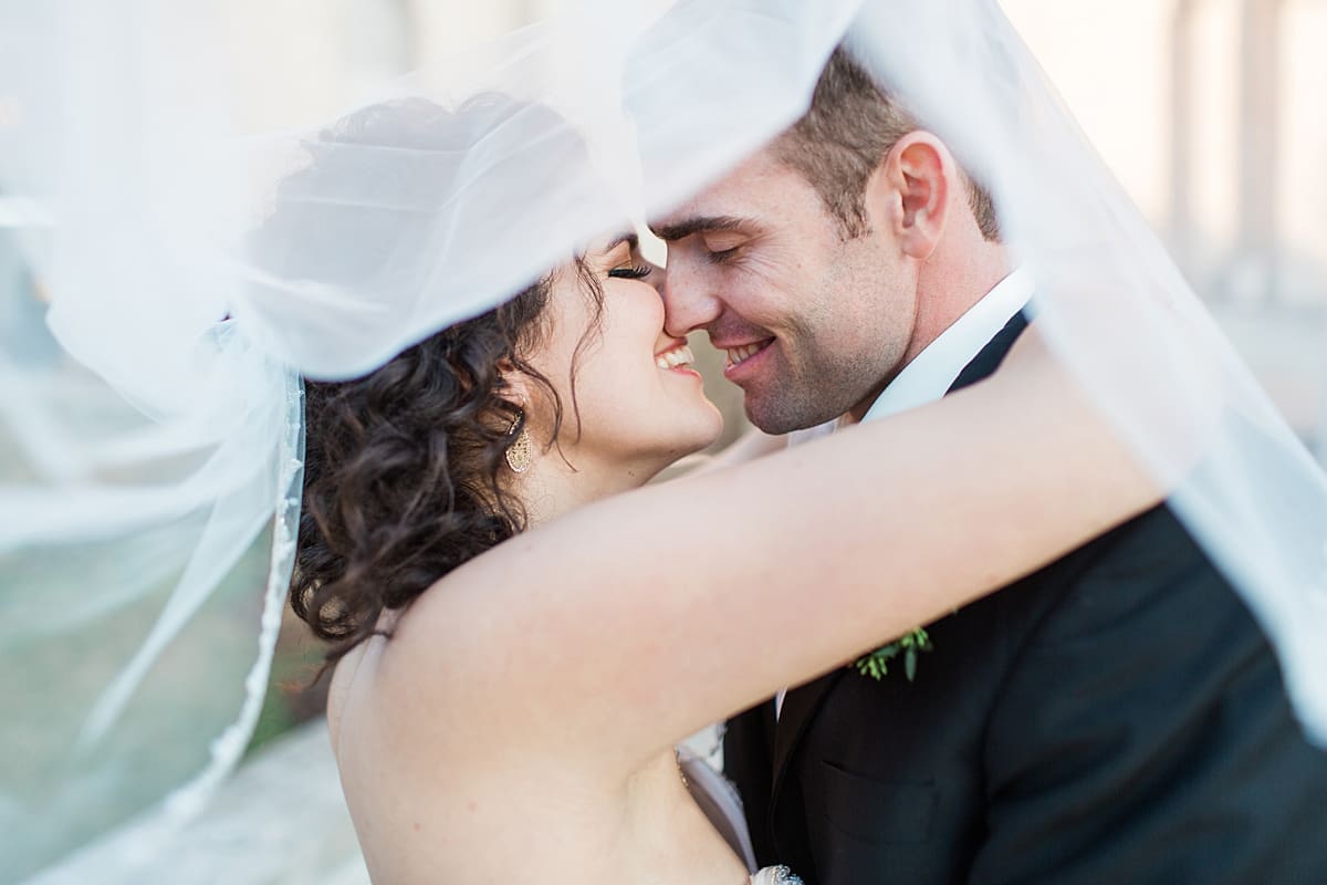Arielle Peters Photography | Bride and groom almost kissing under bouquet on wedding day.