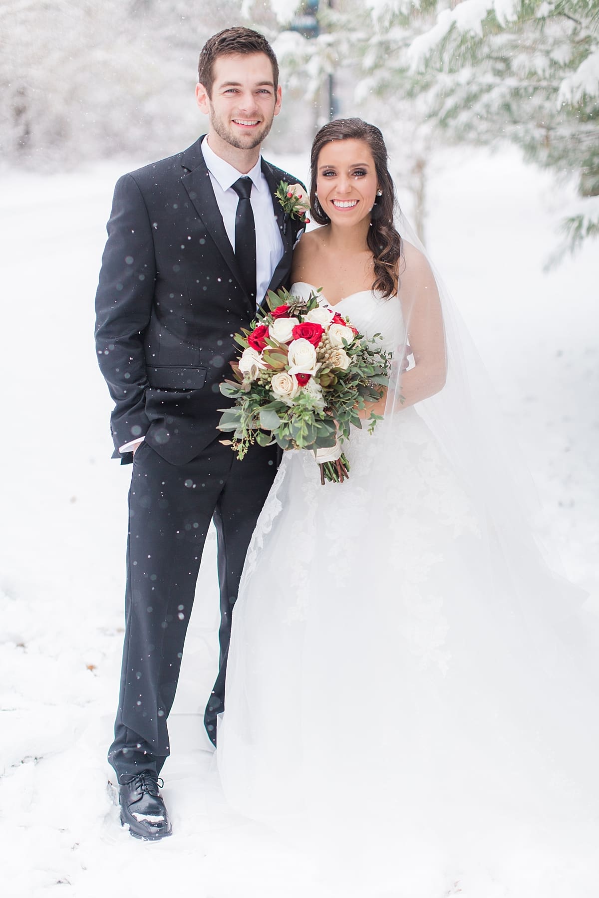 Arielle Peters Photography | Bride and groom in the snow under large pine trees on winter wedding day in Goshen, Indiana.