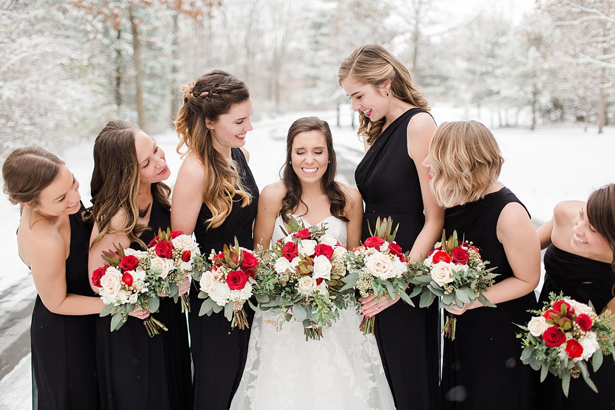 Arielle Peters Photography | Bride and bridesmaids in the snow under large pine trees on winter wedding day in Goshen, Indiana.