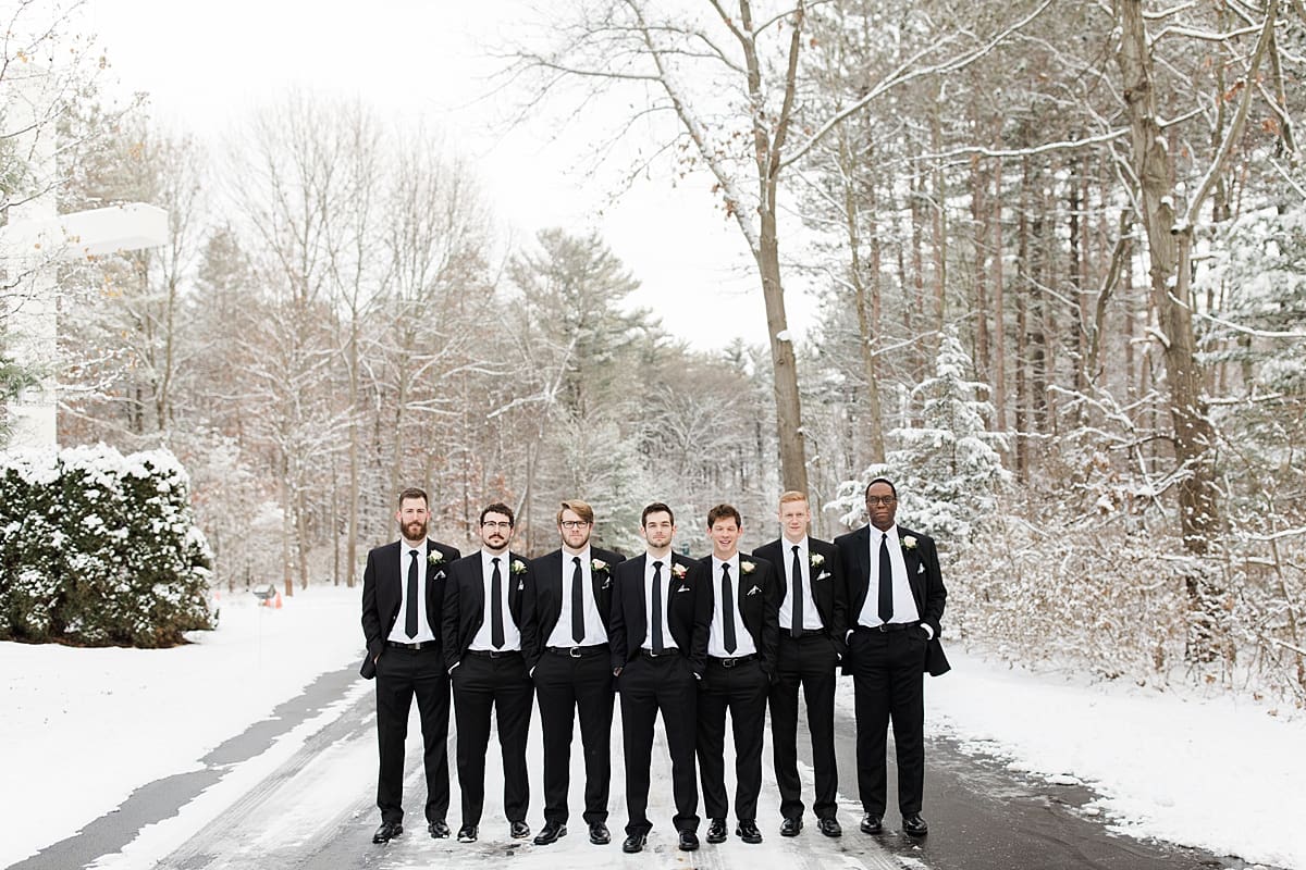 Arielle Peters Photography | Groom and groomsmen in the snow under large pine trees on winter wedding day in Goshen, Indiana.