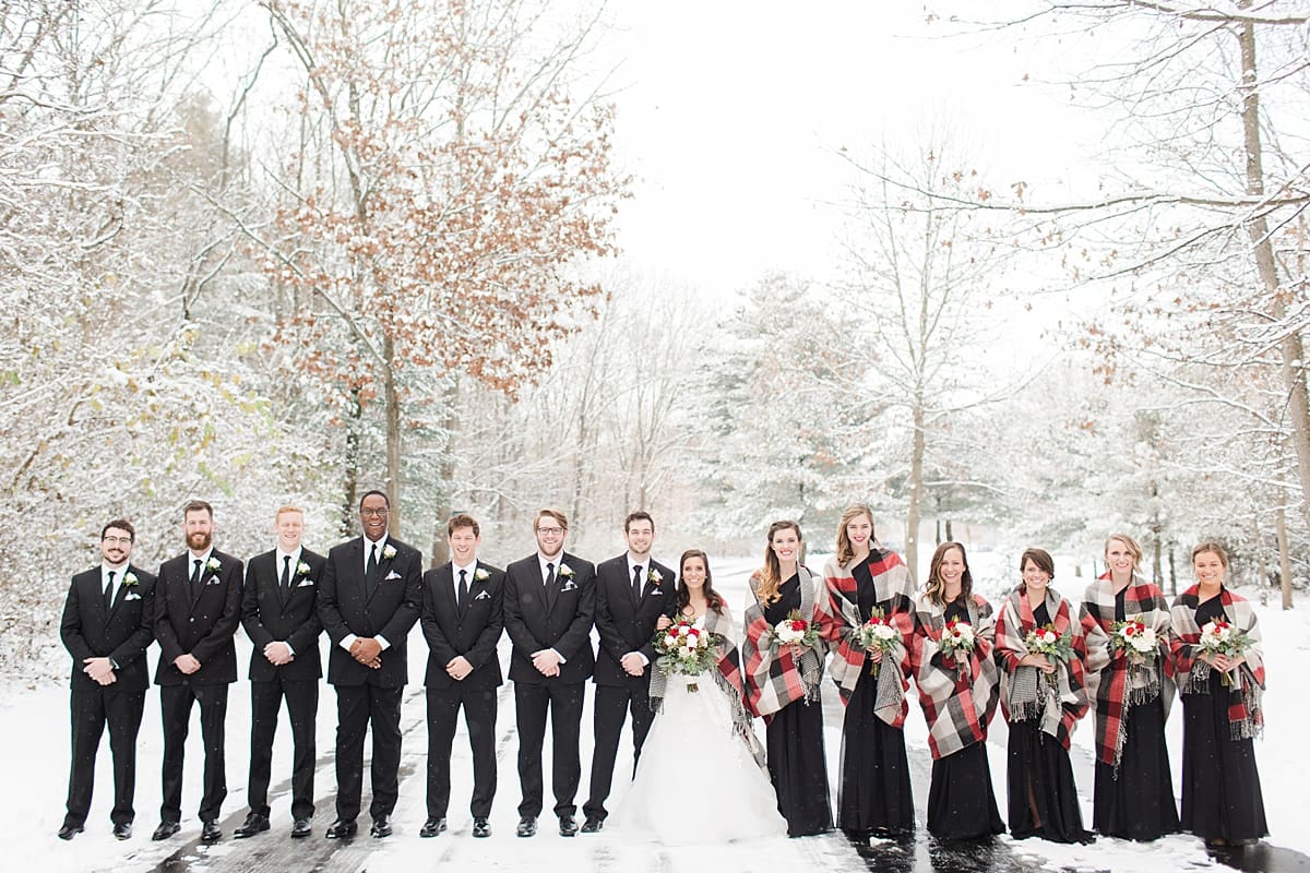 Arielle Peters Photography | Wedding party on snowy streets under large pine trees on winter wedding day in Goshen, Indiana.