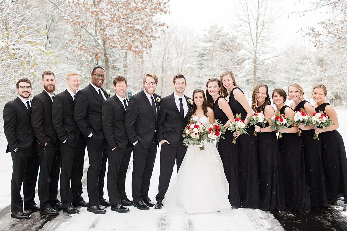 Arielle Peters Photography | Wedding party outside in the snow under large pine trees on winter wedding day in Goshen, Indiana.