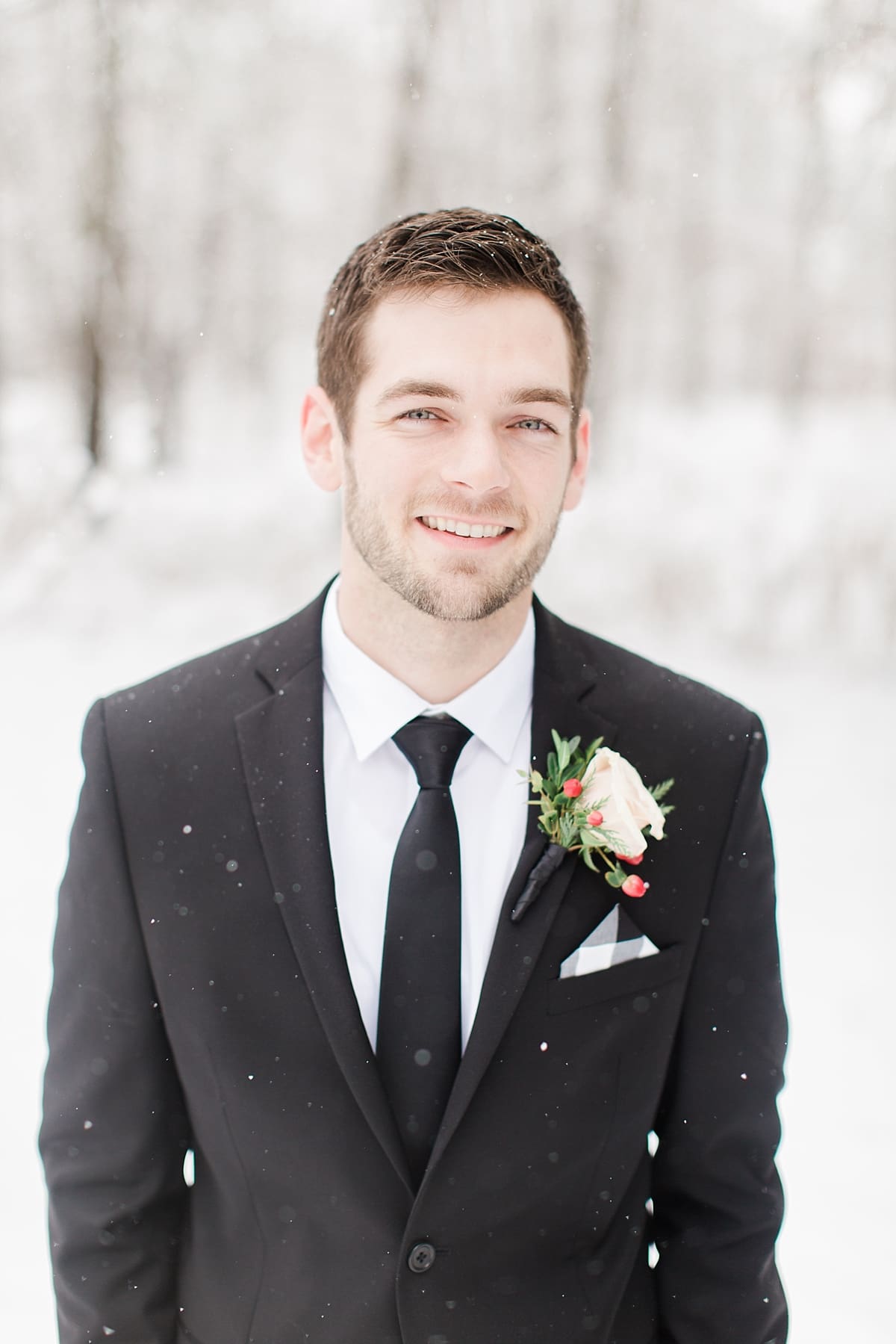 Arielle Peters Photography | Groom smiling in the snow under large pine trees on winter wedding day in Goshen, Indiana.