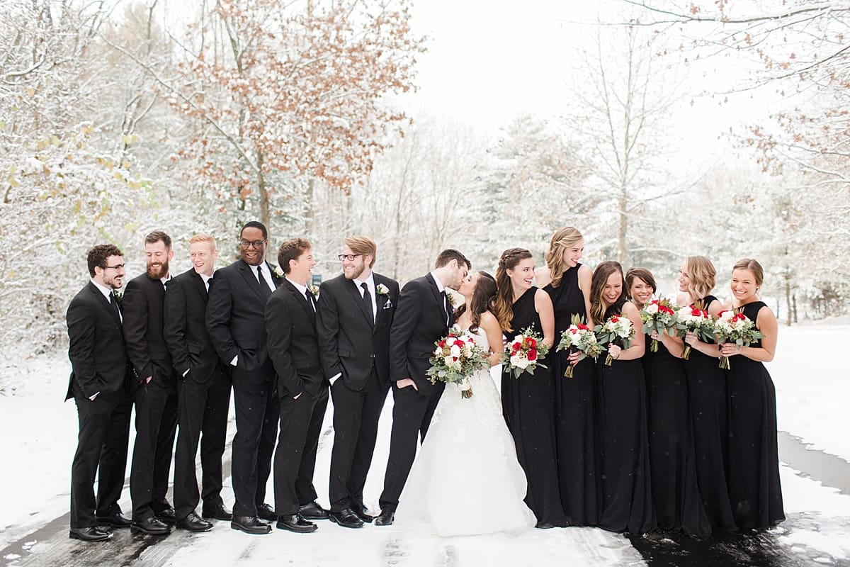 Arielle Peters Photography | Wedding party on snowy streets under large pine trees on winter wedding day in Goshen, Indiana.