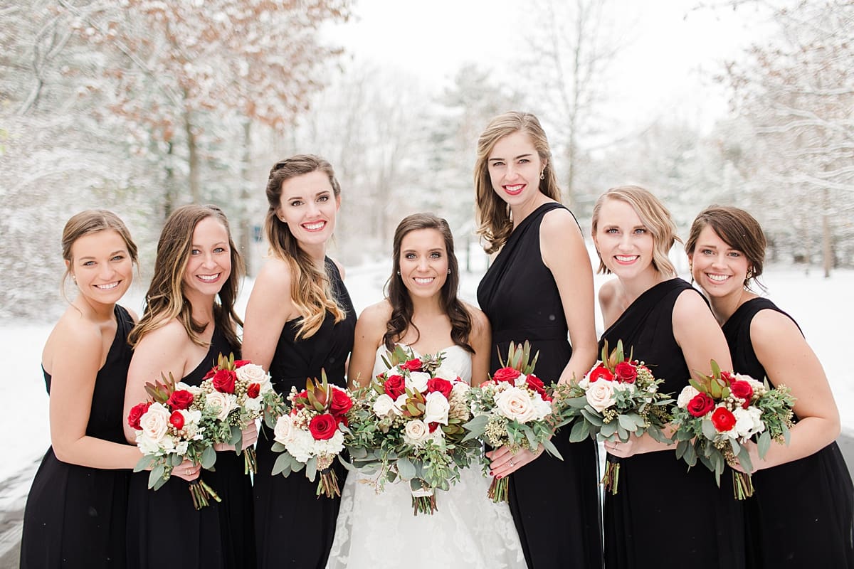 Arielle Peters Photography | Bride and bridesmaids outside in the snow under large pine trees on winter wedding day in Goshen, Indiana.