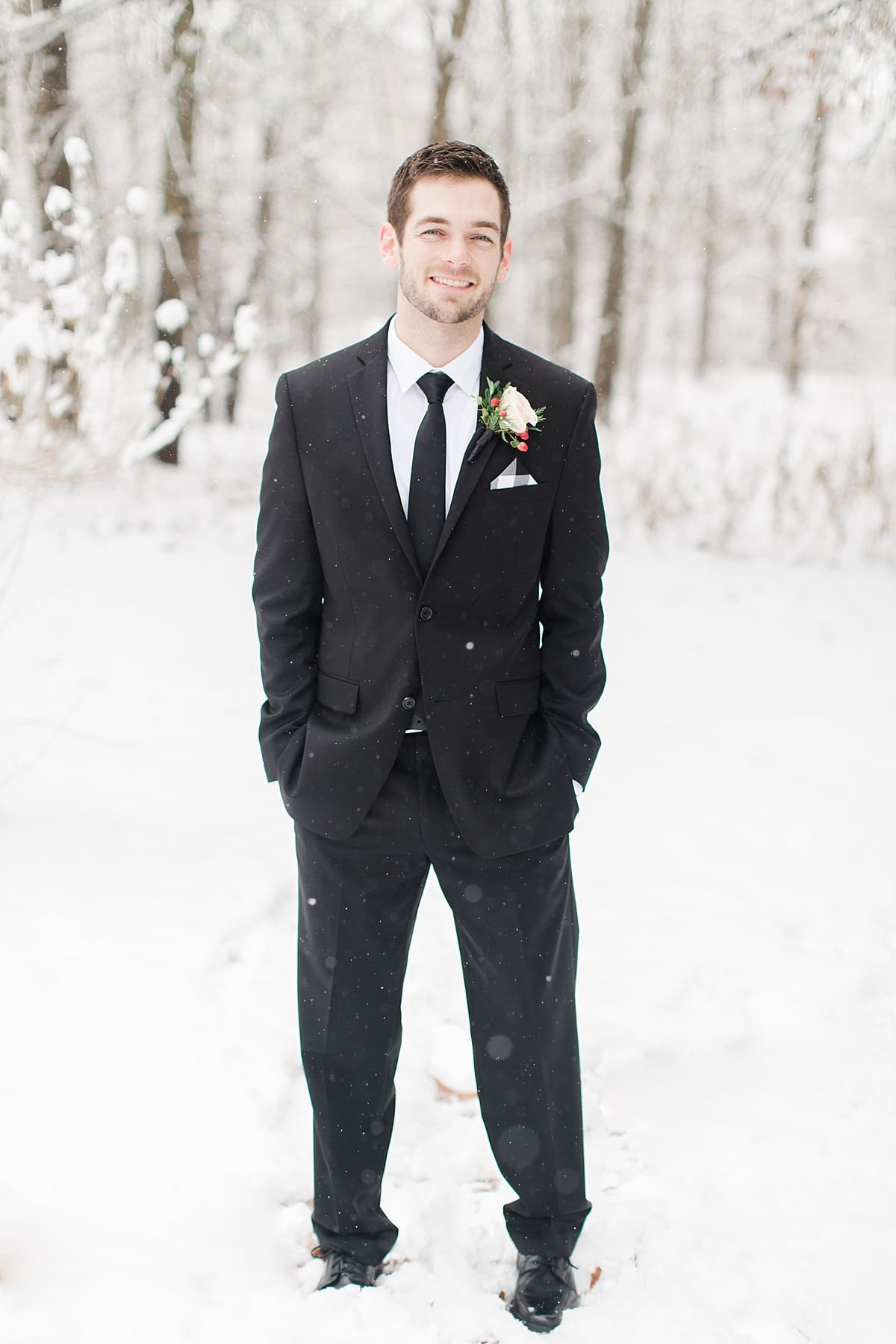 Arielle Peters Photography | Groom in the snow under large pine trees on winter wedding day in Goshen, Indiana.