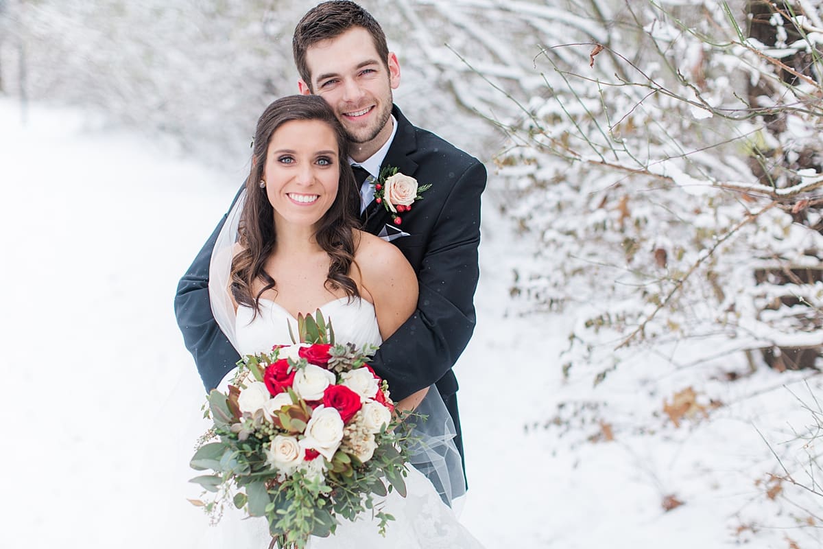 Arielle Peters Photography | Bride and groom in the snow under large pine trees on winter wedding day in Goshen, Indiana.