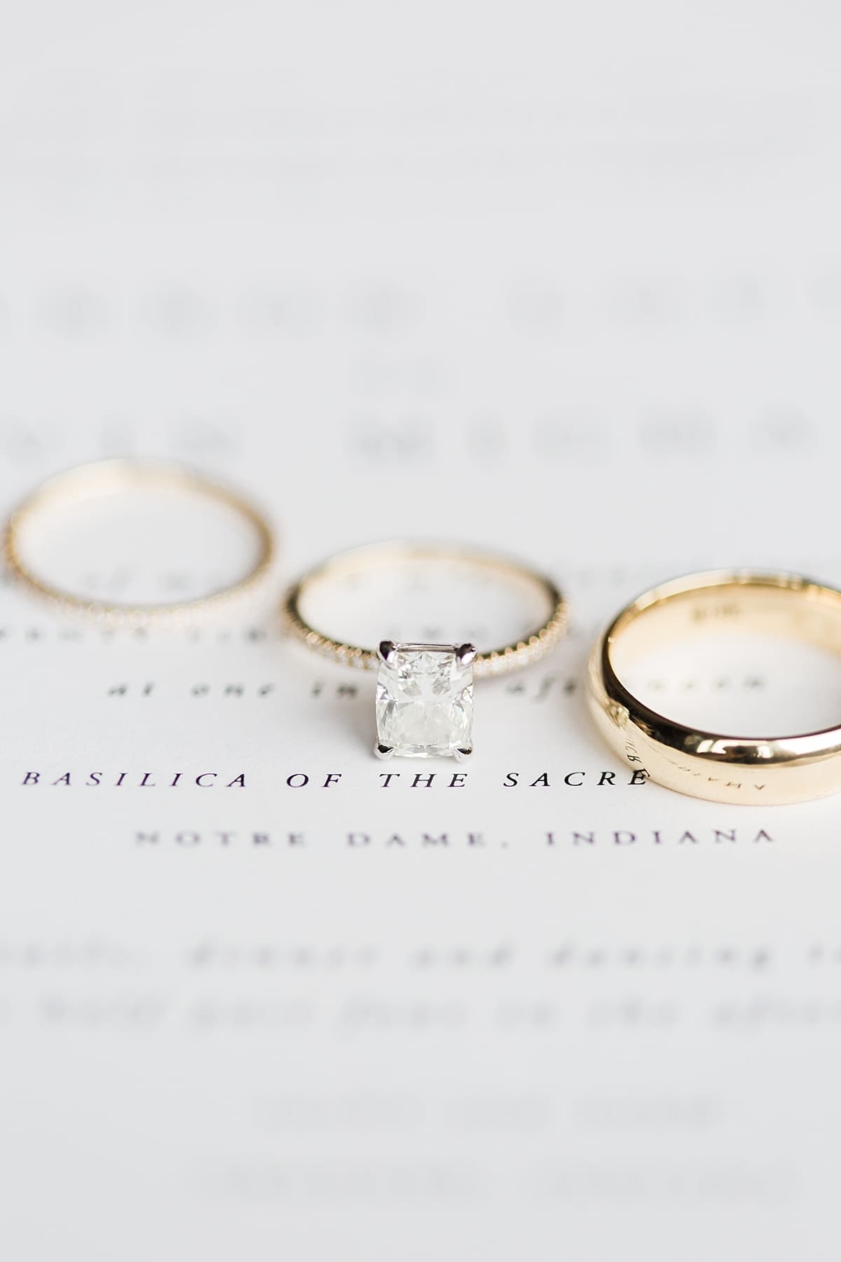 Arielle Peters Photography | Wedding rings on invitation on wedding day inside the Basilica of the Sacred Heart in Notre Dame, Indiana.
