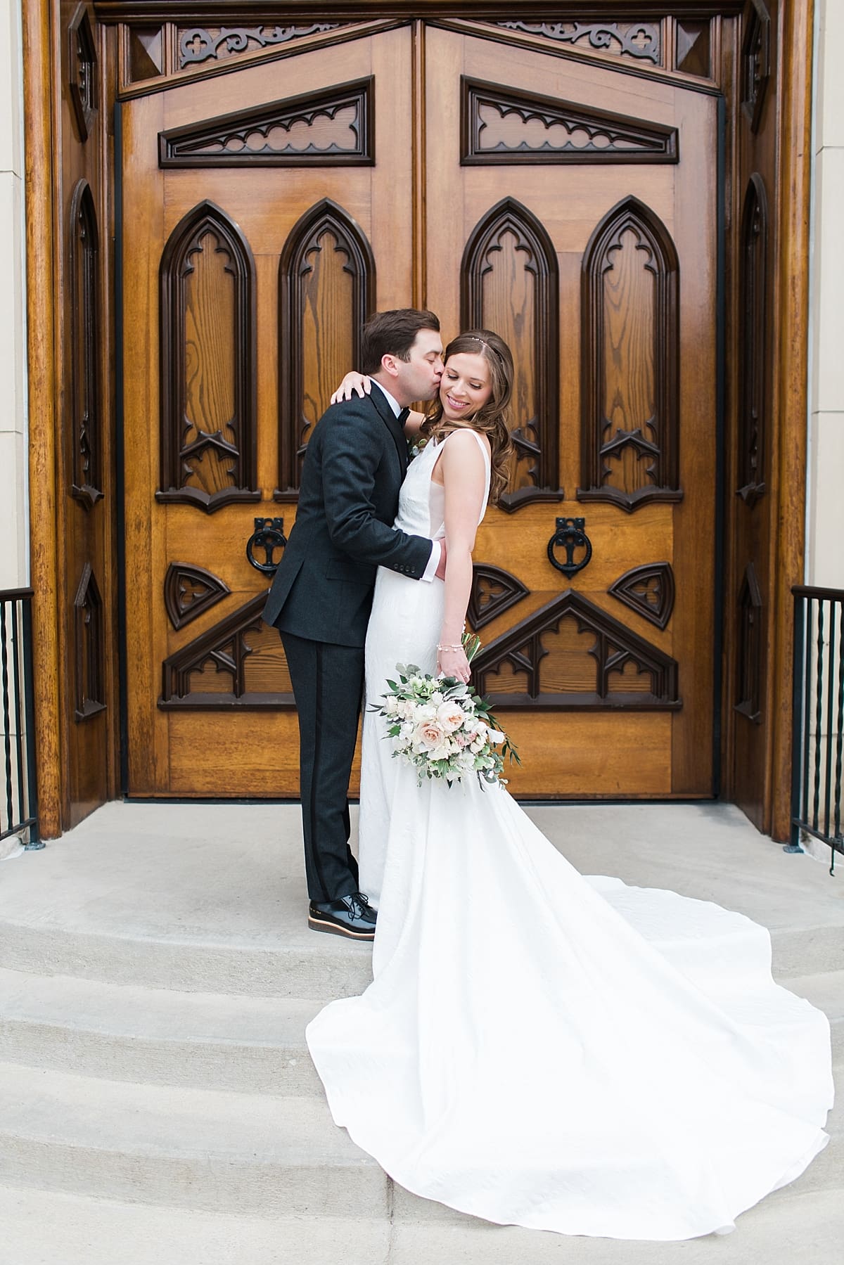 Arielle Peters Photography | Bride and groom kissing in front of cathedral doors on wedding day at the Basilica of the Sacred Heart in Notre Dame, Indiana.
