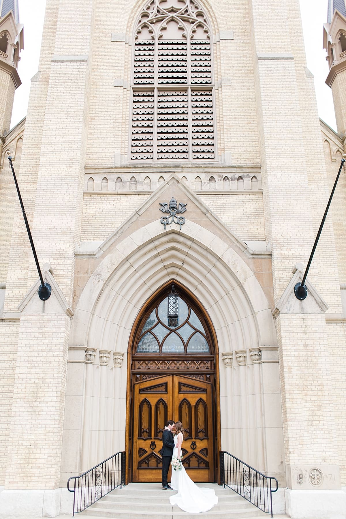 Arielle Peters Photography | Bride and groom kissing in front of cathedral doors on wedding day at the Basilica of the Sacred Heart in Notre Dame, Indiana.