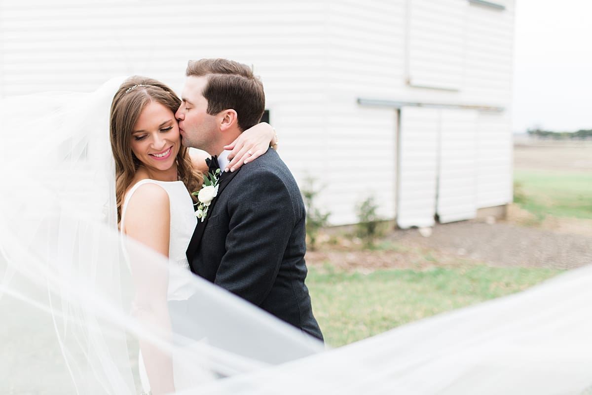 Arielle Peters Photography | Bride and groom kissing in front of barn on wedding day at St. Joseph's Farm in Granger, Indiana.