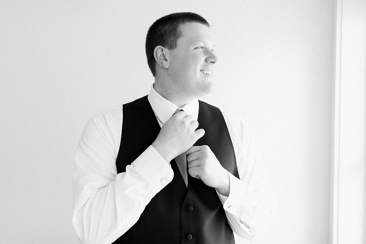 Arielle Peters Photography | Groom adjusting his tie getting ready on wedding day in Winona Lake, Indiana. 
