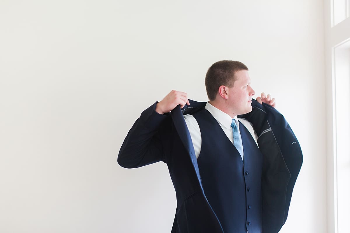 Arielle Peters Photography | Groom putting on tux jacket on wedding day in Winona Lake, Indiana. 