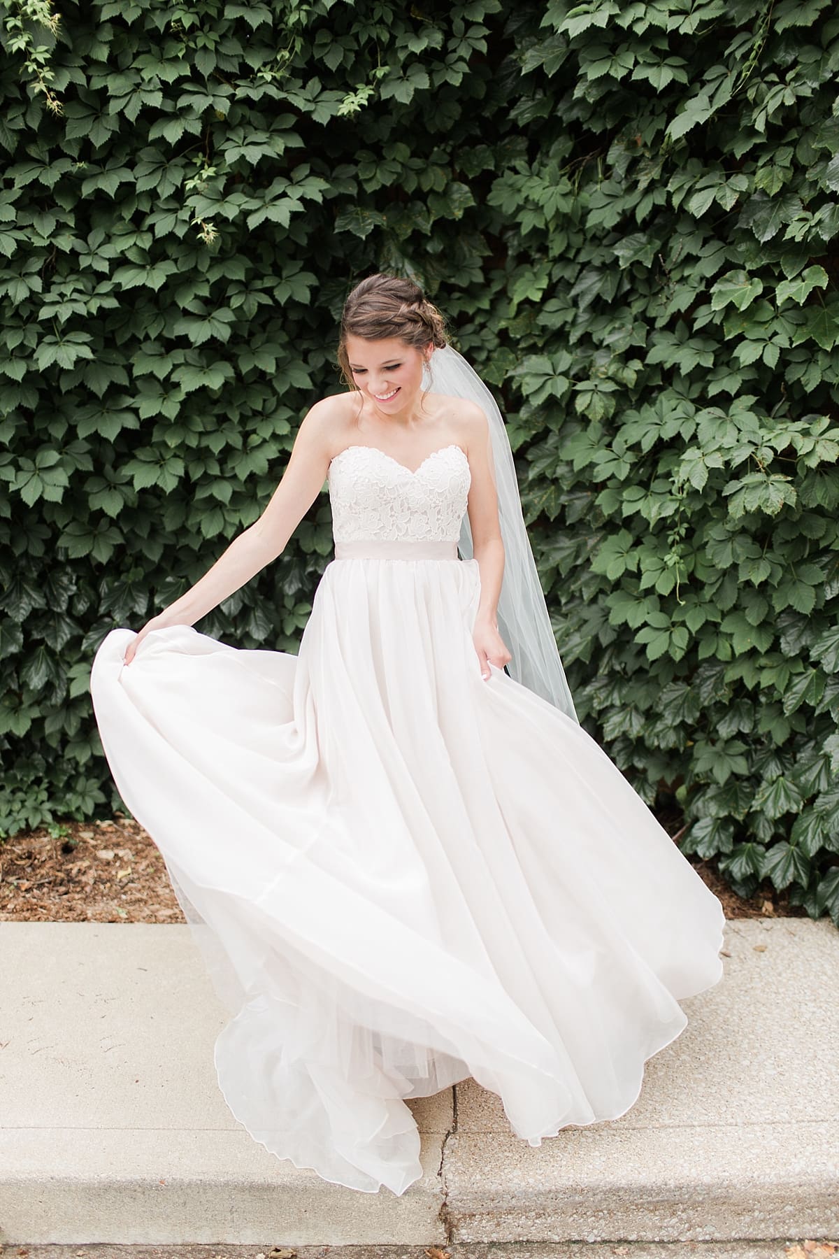 Arielle Peters Photography | Bride twirling by ivy-covered wall on wedding day at Morris Park Country Club in South Bend, Indiana.
