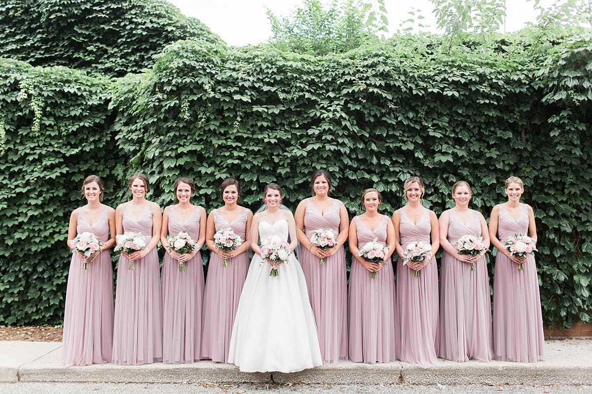 Arielle Peters Photography | Bride and bridesmaids standing by ivy-covered wall on wedding day at Morris Park Country Club in South Bend, Indiana.