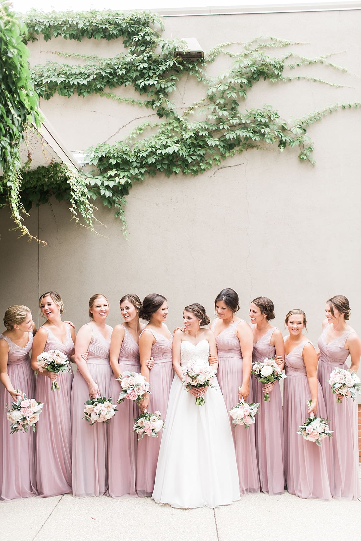 Arielle Peters Photography | Bride and bridesmaids by ivy-covered wall on wedding day at Morris Park Country Club in South Bend, Indiana.