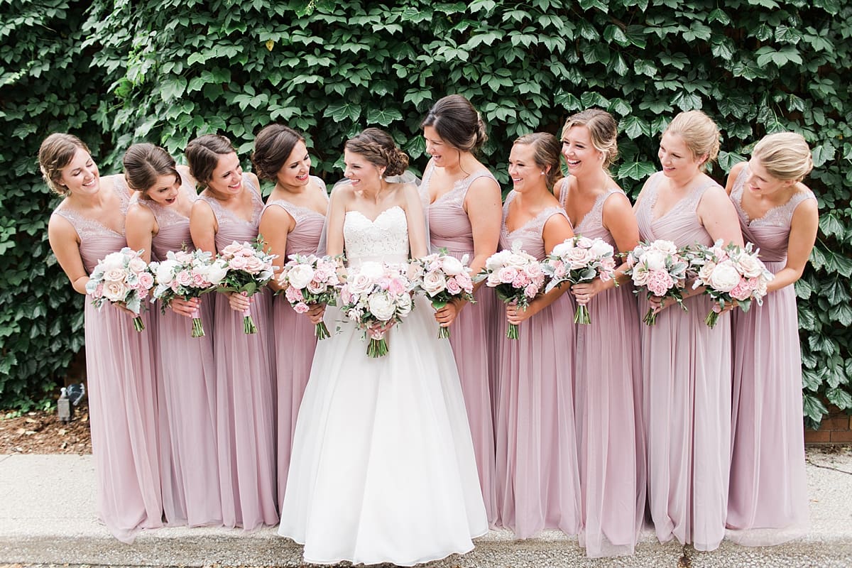 Arielle Peters Photography | Bride and bridesmaids standing by ivy-covered wall on wedding day at Morris Park Country Club in South Bend, Indiana.