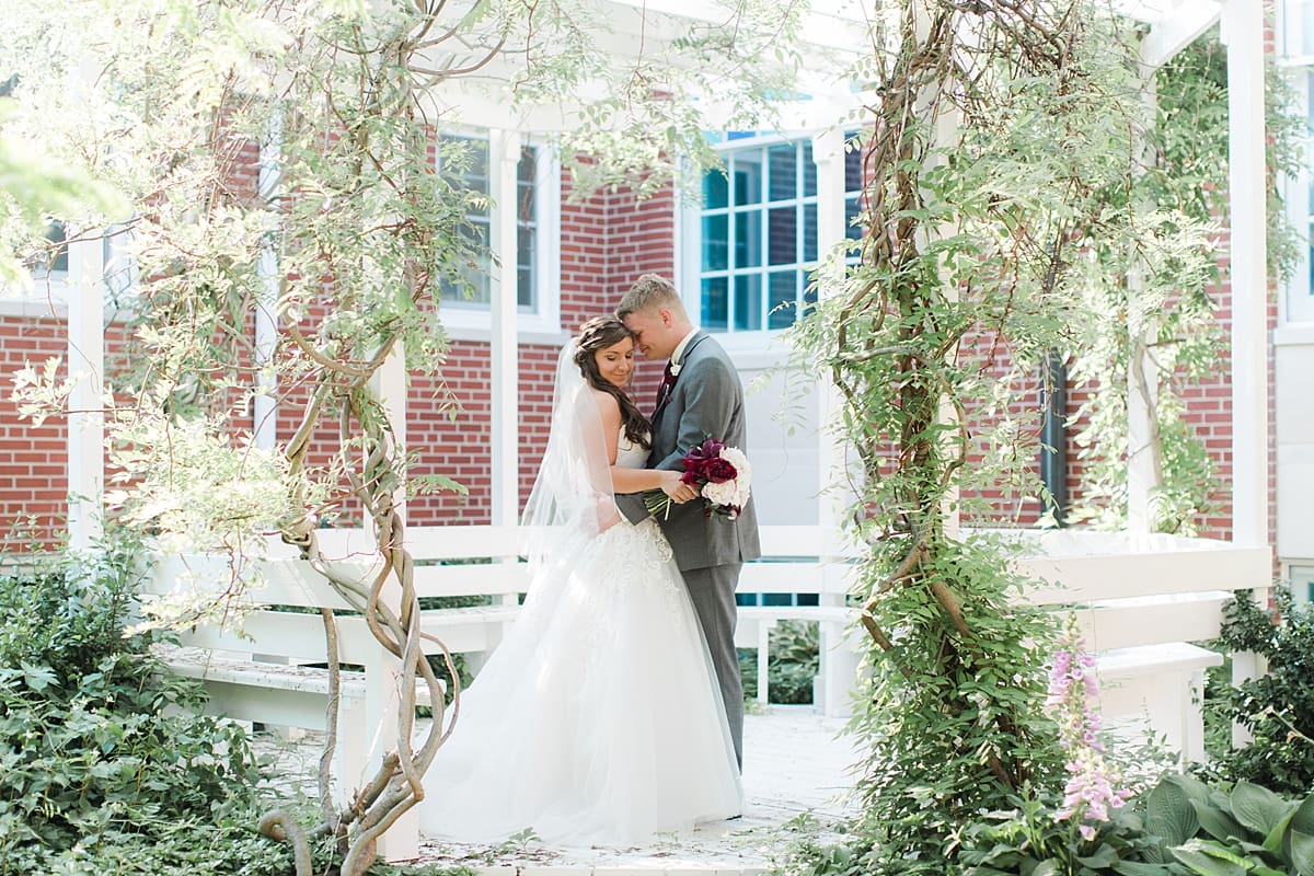Arielle Peters Photography | Bride and groom under over-grown trellis on wedding day at Trinity Church in South Bend, Indiana.