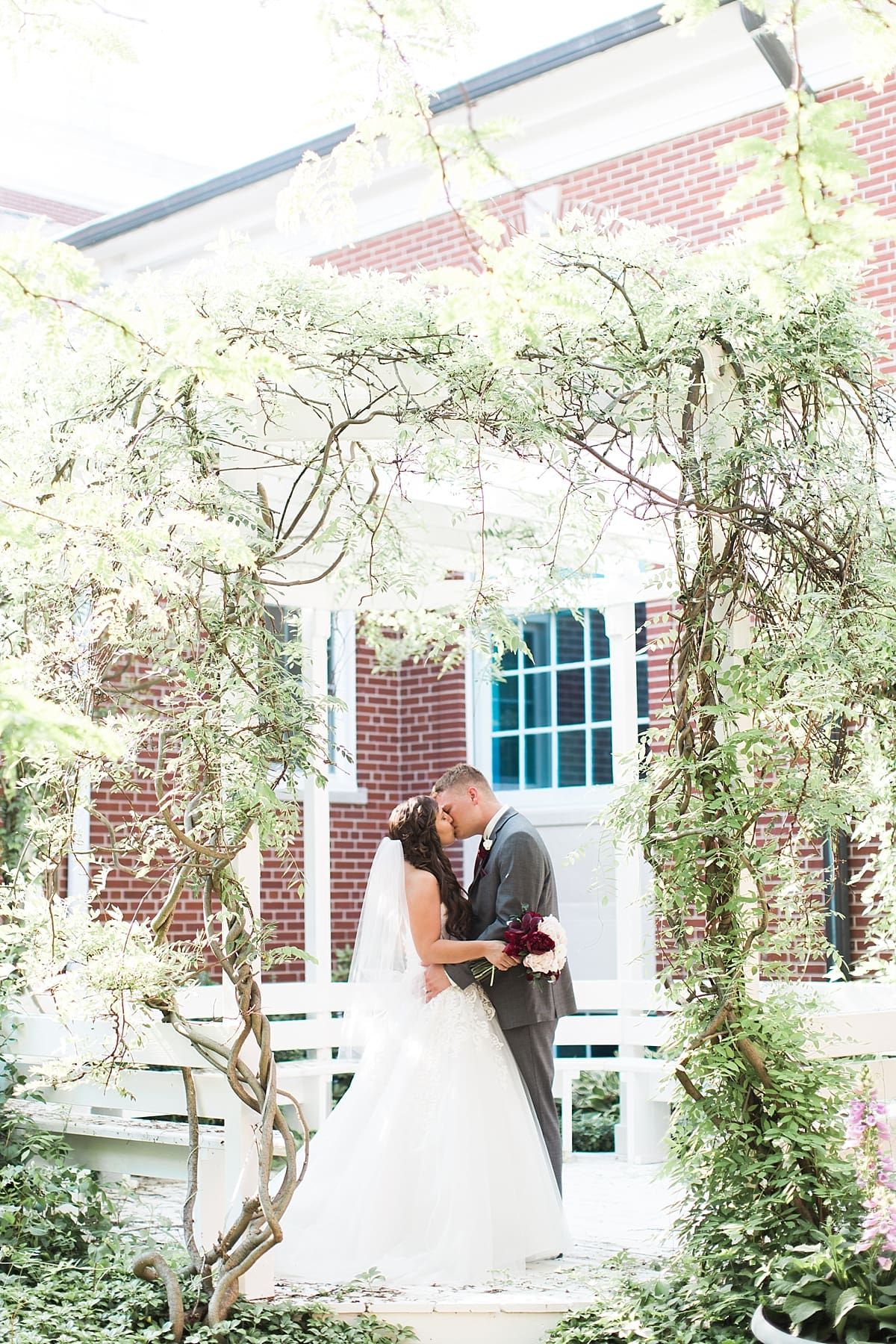 Arielle Peters Photography | Bride and groom under over-grown trellis on wedding day at Trinity Church in South Bend, Indiana.