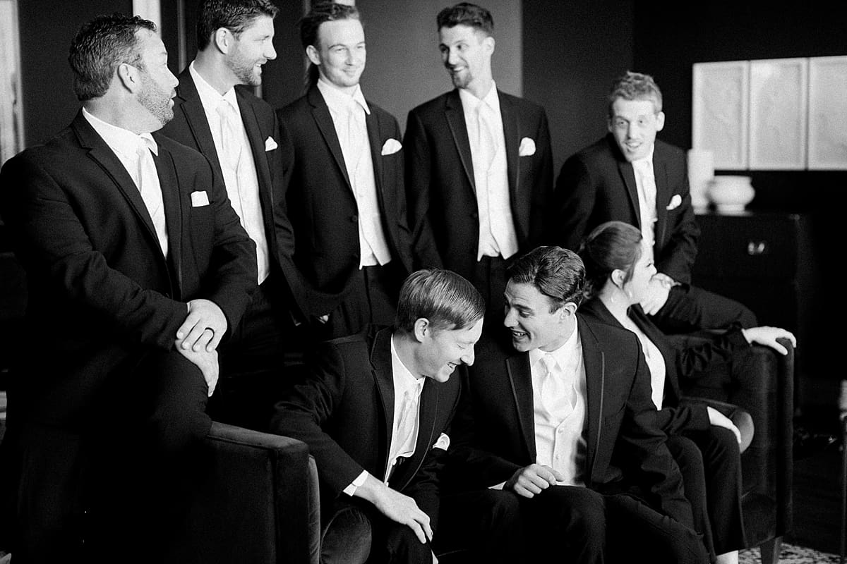 Arielle Peters Photography | Groom and groomsmen laughing on velvet couch on wedding day at Loft 310 in Kalamazoo, Michigan.