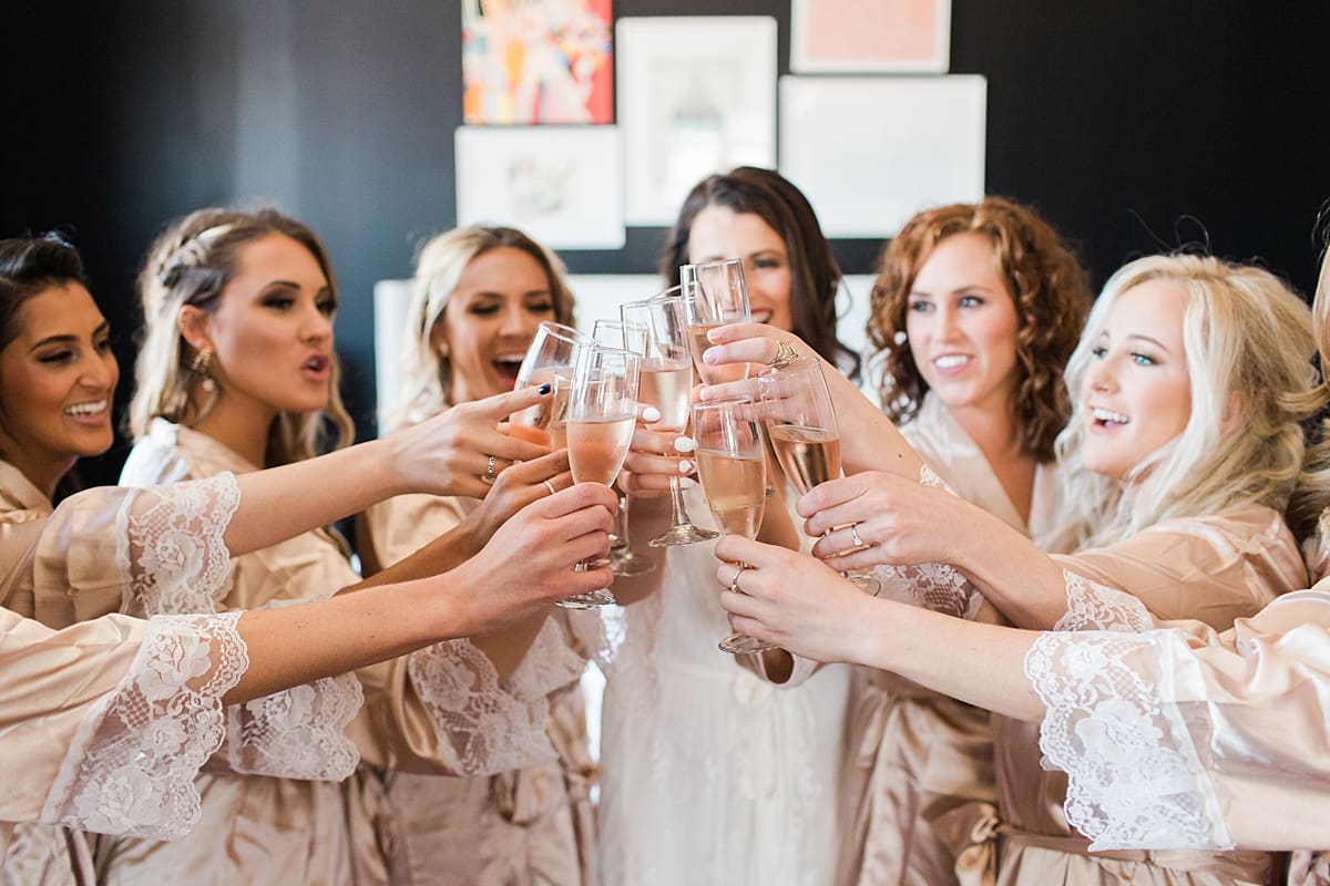 Arielle Peters Photography | Bride and bridesmaids raising a glass in robes on wedding day at Loft 310 in Kalamazoo, Michigan.