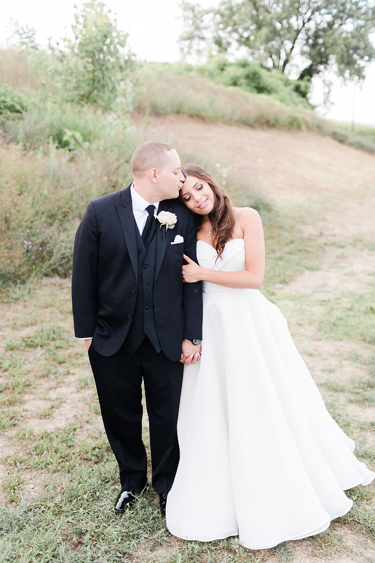 Arielle Peters Photography | Bride and groom kissing by the water on wedding day at The Inn at Harbor Springs in St. Joseph, Michigan.