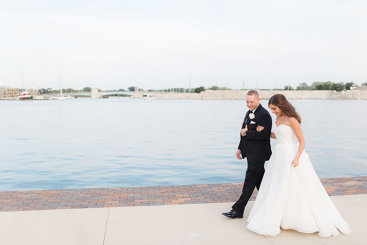 Arielle Peters Photography | Bride and groom walking by the water on wedding day at The Inn at Harbor Springs in St. Joseph, Michigan.