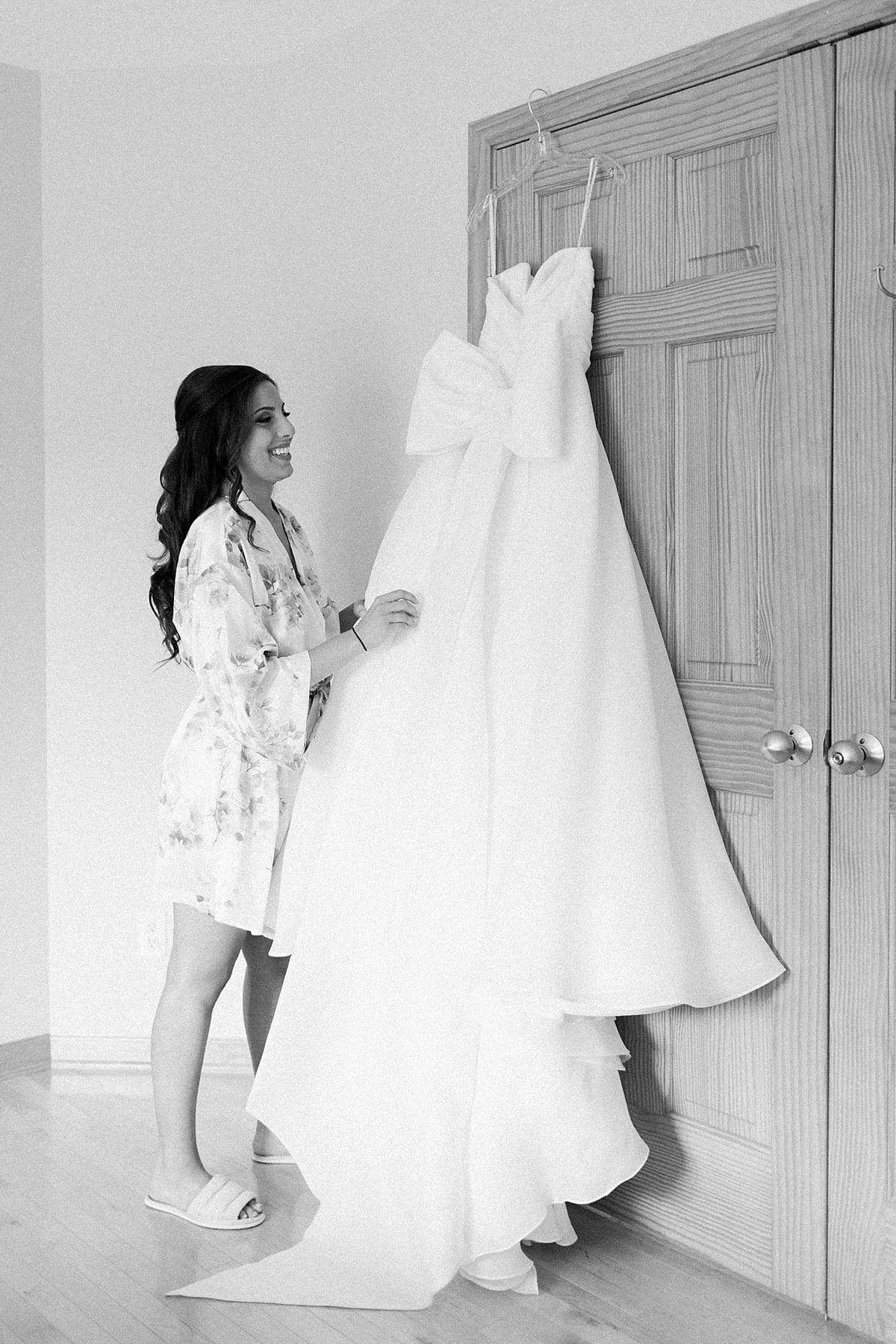 Arielle Peters Photography | Bride looking at wedding gown hanging on wedding day at The Inn at Harbor Springs in St. Joseph, Michigan.