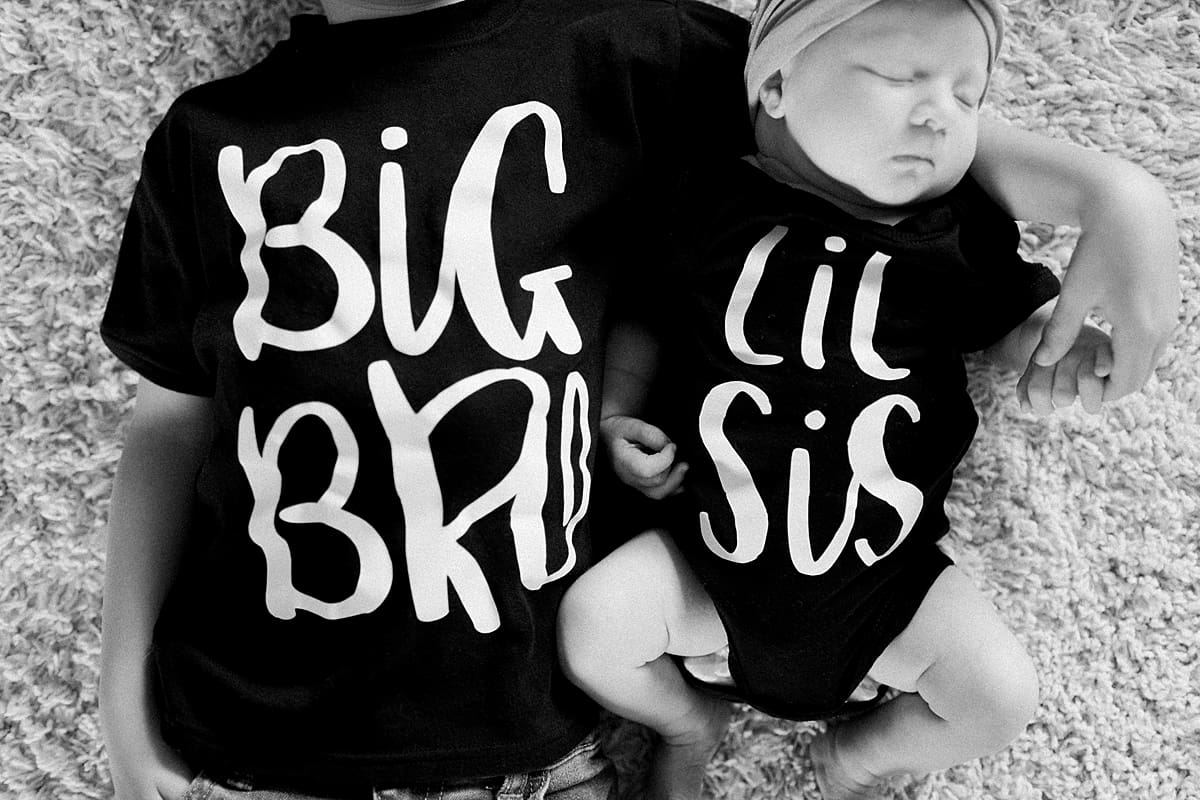 Arielle Peters Photography | Big brother posing with his newborn baby sister in matching t-shirts. 