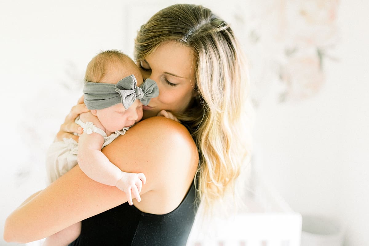 Arielle Peters Photography | Mom holding her newborn baby girl in a bow.