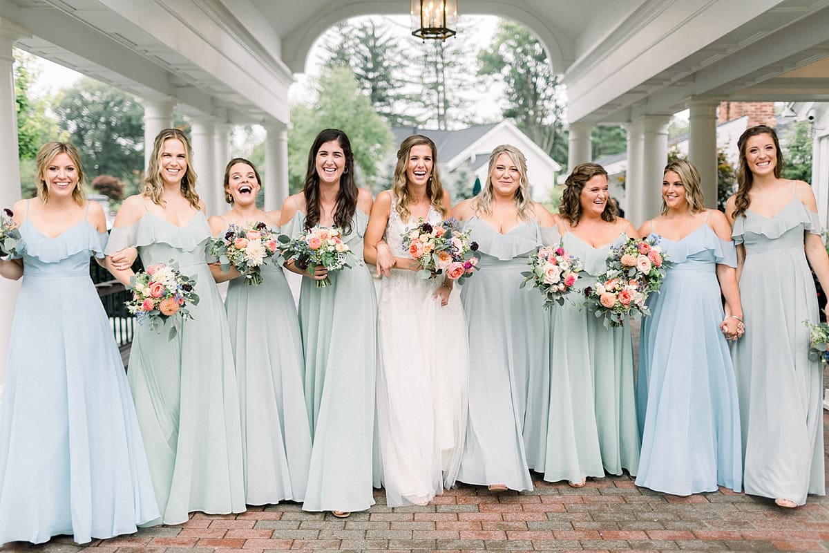 Arielle Peters Photography | Bride and bridesmaids laughing and linking arms outside on wedding day at Sycamore Hills Golf Club in Fort Wayne, Indiana.